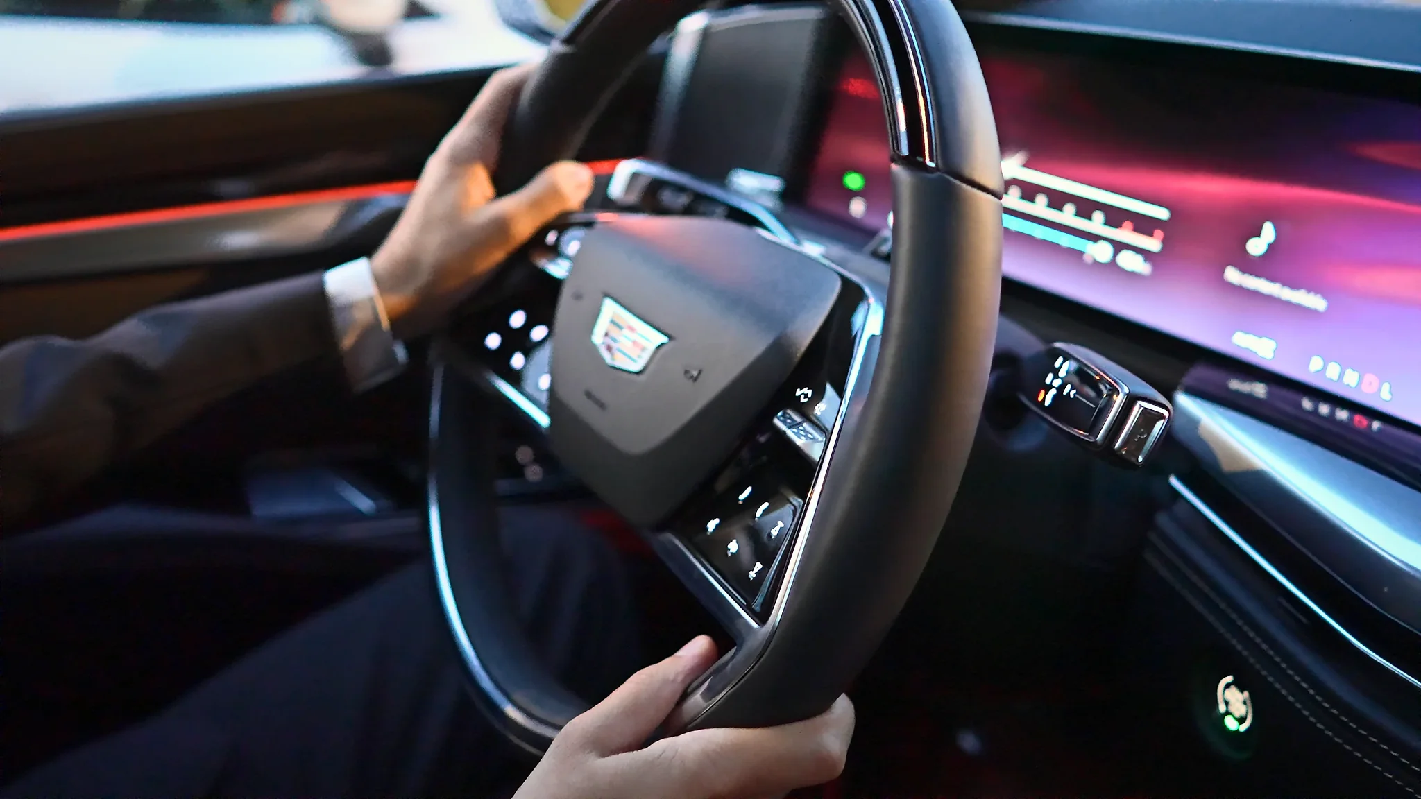 A chauffeur's hands on the wheel of a Cadillac Escalade ESV, dashboard lit