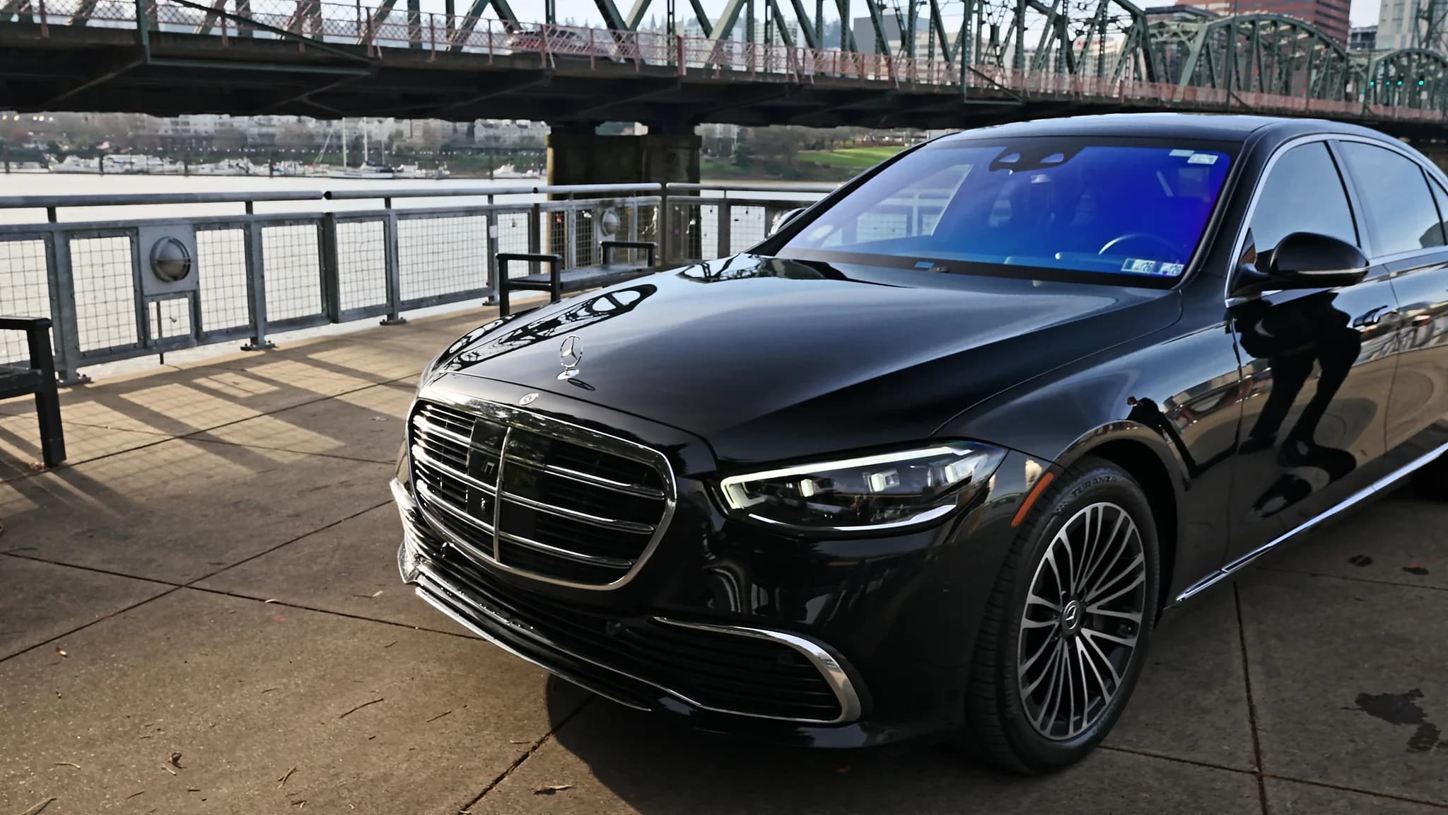 Black chauffeured sedan on the Portland waterfront with the Hawthorne Bridge and downtown behind