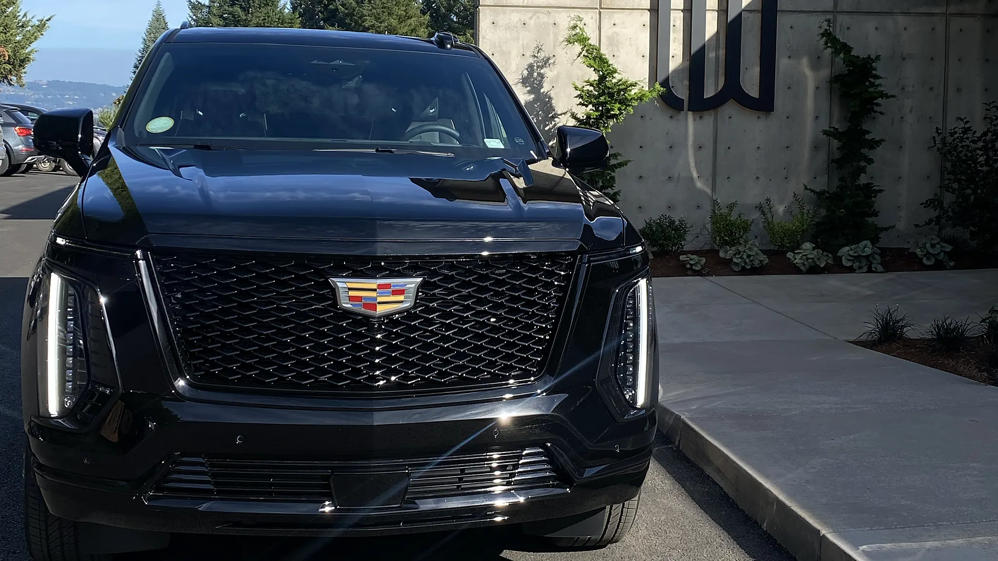 Black Cadillac Escalade parked at a modern concrete building — Marquee Chauffeur fleet vehicle, Portland area