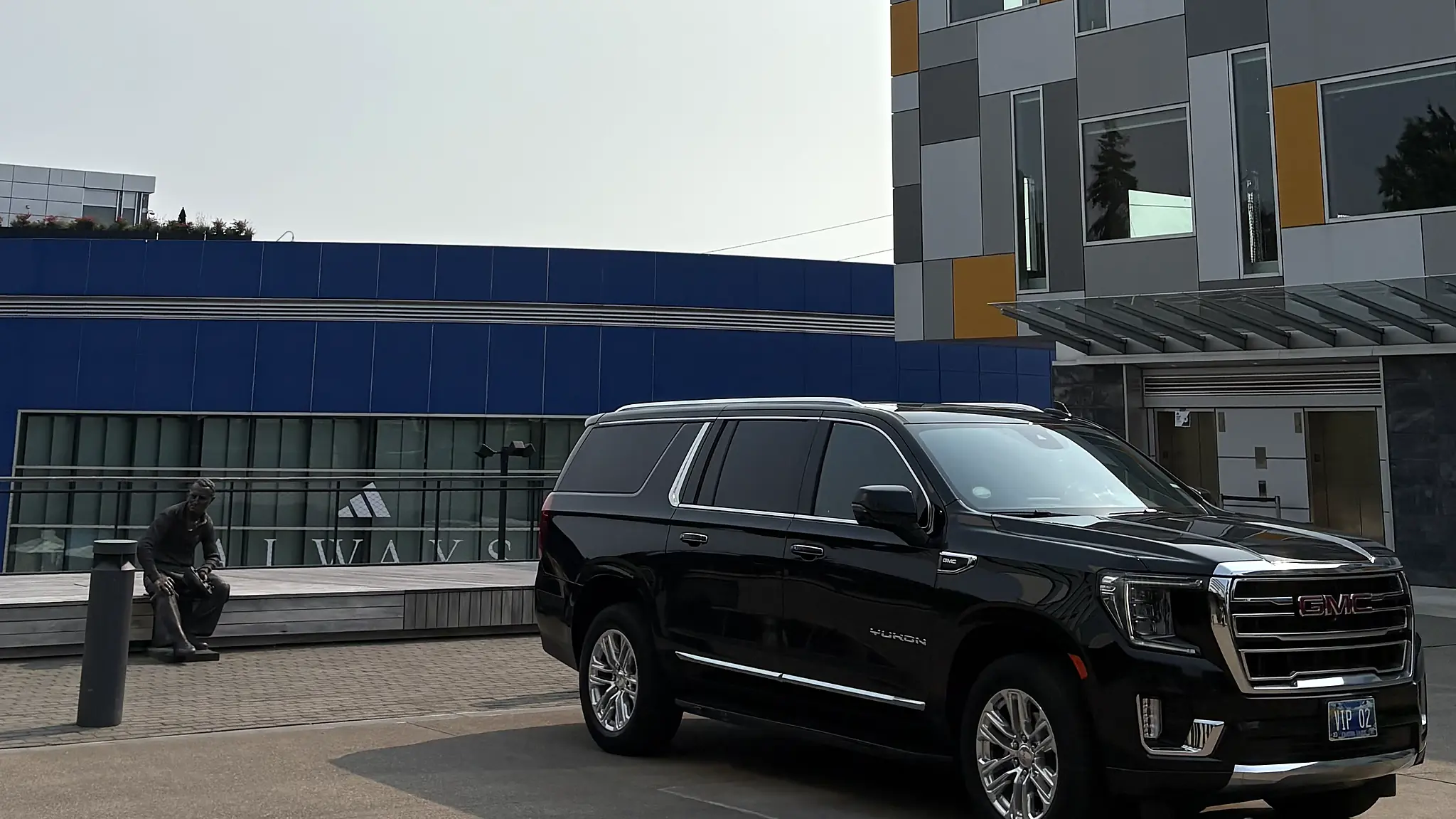 Black chauffeured SUV parked outside a modern office building — executive car service
